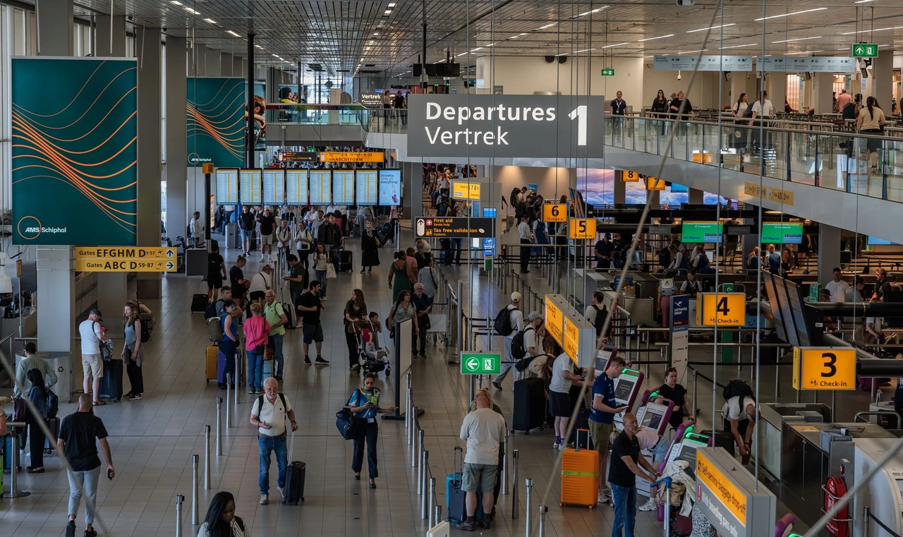 Travelers in the busy departure hall at Amsterdam Schiphol Airport checking flight information
