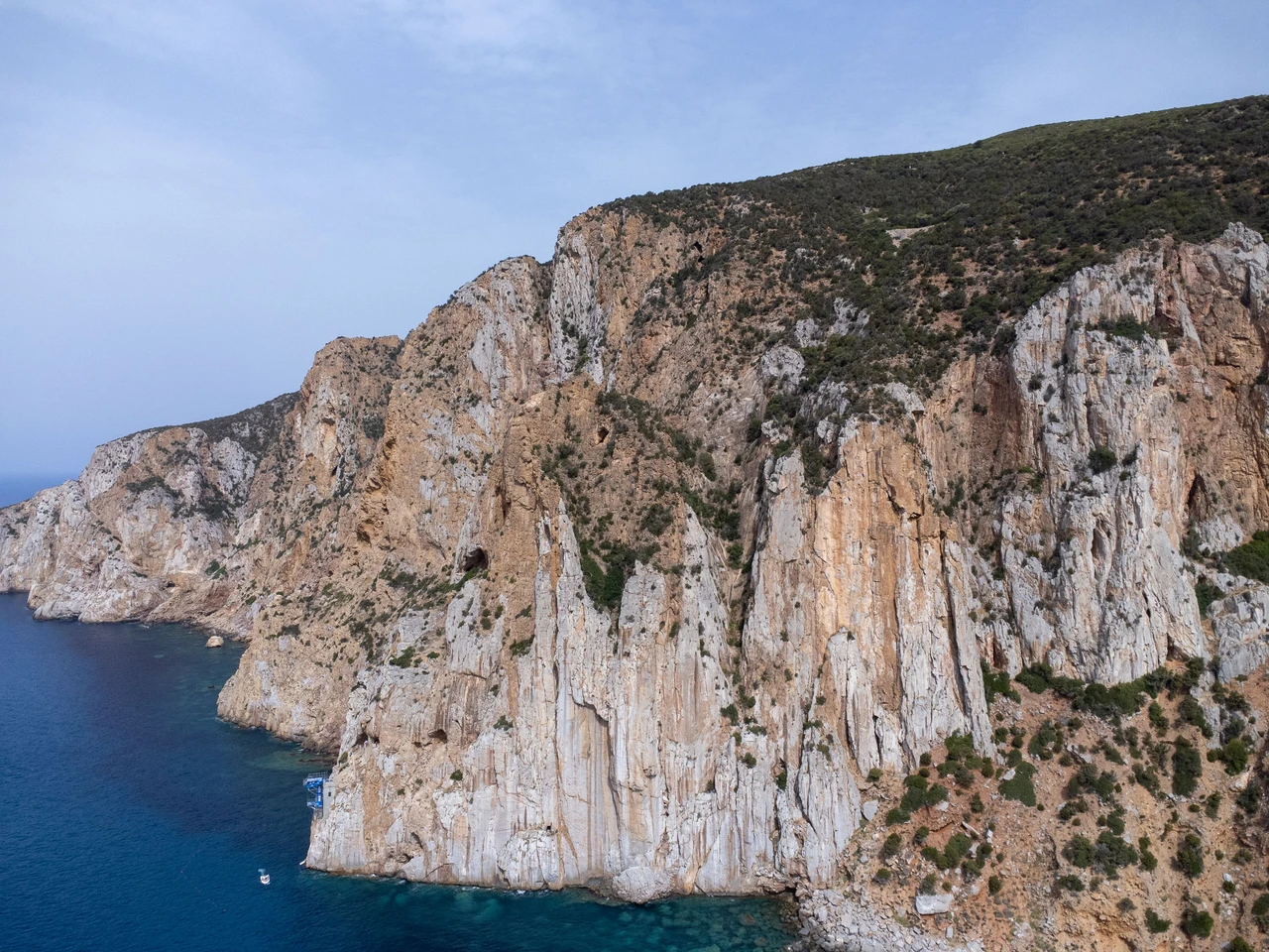 Aerial view of dramatic coastal cliffs and turquoise Mediterranean water in Sardinia, Italy